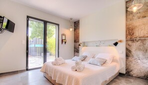 Ein Schlafzimmer mit einem großen Bett, einer Schiebetür zum Balkon und einer Wand mit Steinverkleidung.
