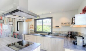 Eine moderne Küche mit großem Fenster, Edelstahlgeräten und minimalistischem Design.