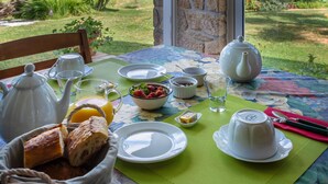 A breakfast table set with white teapots, cups, a bowl of strawberries, bread, and a green placemat. - Guest Room 'Le Cèdre Bleu' with Shared Terrace & Garden, Wi-Fi (Rochechouart)