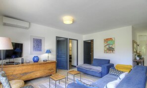 Ein Wohnzimmer mit einer Couch, einem Couchtisch, einem Fernseher und einer Holzkommode.