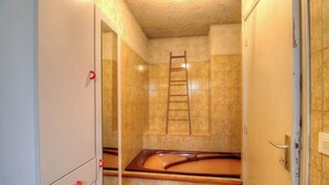 Un baño con bañera, una escalera de madera y un espejo.