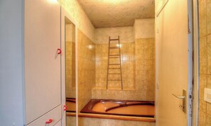 Une salle de bain avec une baignoire, une échelle en bois et un miroir.