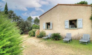 Une maison avec un jardin, une terrasse avec des chaises et une petite piscine.