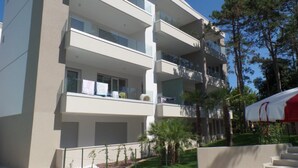 Un edificio de varios pisos con balcones, una piscina y una carpa roja y blanca.