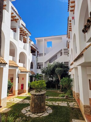 A courtyard with white buildings, stone pathways, and greenery. - Apartment at the foot of Sierra de Irta, Hiking, Nature, Mountain and Sea. (Peñíscola)