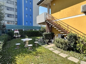 Ein Innenhof mit kleinem Garten, einer Treppe und einem Gebäude mit blau-gelber Fassade.