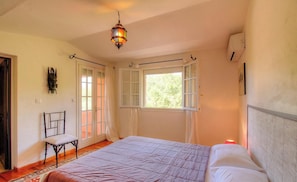 A bedroom with a bed, a chair, a hanging lamp, and a window. - Le 26991 - SAN GAVINO DI CARBINI (SAN GAVINO DI CARBINI)