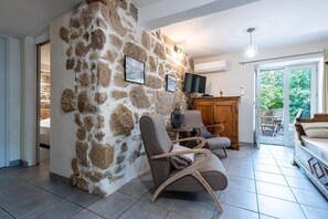 Ein Wohnzimmer mit Steinsäulen, einem Fernseher, einem Holzschrank und einem Sofa.