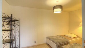 A bedroom with a bed, a bedside table, a lamp, and a metal shelf unit. - Villa di Charma Charlotte (CALCATOGGIO)