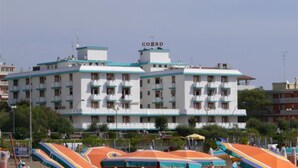 A multi-story hotel with balconies, a sign reading 'GORSO' on the roof, and outdoor umbrellas. - Sea view flat in Bibione for four guests (Bibione)