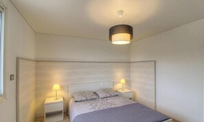 A bedroom with a bed, two bedside tables, a hanging light fixture, and a window. - Villa di Charma Marion (CALCATOGGIO)