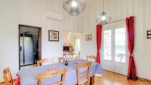 A dining area with a table set for six, wooden chairs, a chandelier, and a view of the kitchen and outside. - In the Meadow of the Kites - CUTTOLI CORTICCHIATO (CUTTOLI CORTICCHIATO)