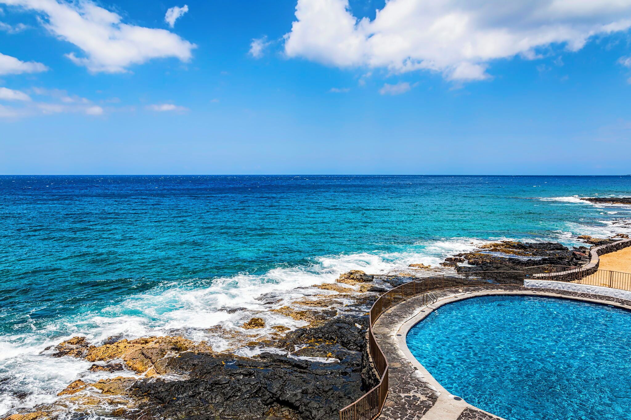 Une piscine offrant une vue sur l’océan et la côte rocheuse.