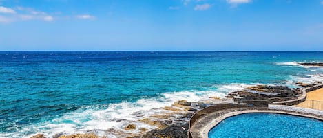 A pool with a view of the ocean and rocky coastline.