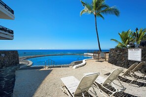 Ein Pool mit Blick auf den Ozean, Liegestühle und ein Schild mit den Poolregeln.