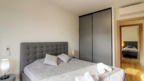 A neatly made bed with a grey headboard, a bedside lamp, and a bedside table with a lamp. - Villa Bella Vista - SAN GAVINO DI CARBINI (SAN GAVINO DI CARBINI)