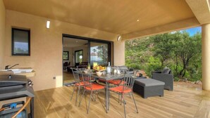 An outdoor dining area with a table and chairs, a grill, and a view of greenery. - Villa Bella Vista - SAN GAVINO DI CARBINI (SAN GAVINO DI CARBINI)