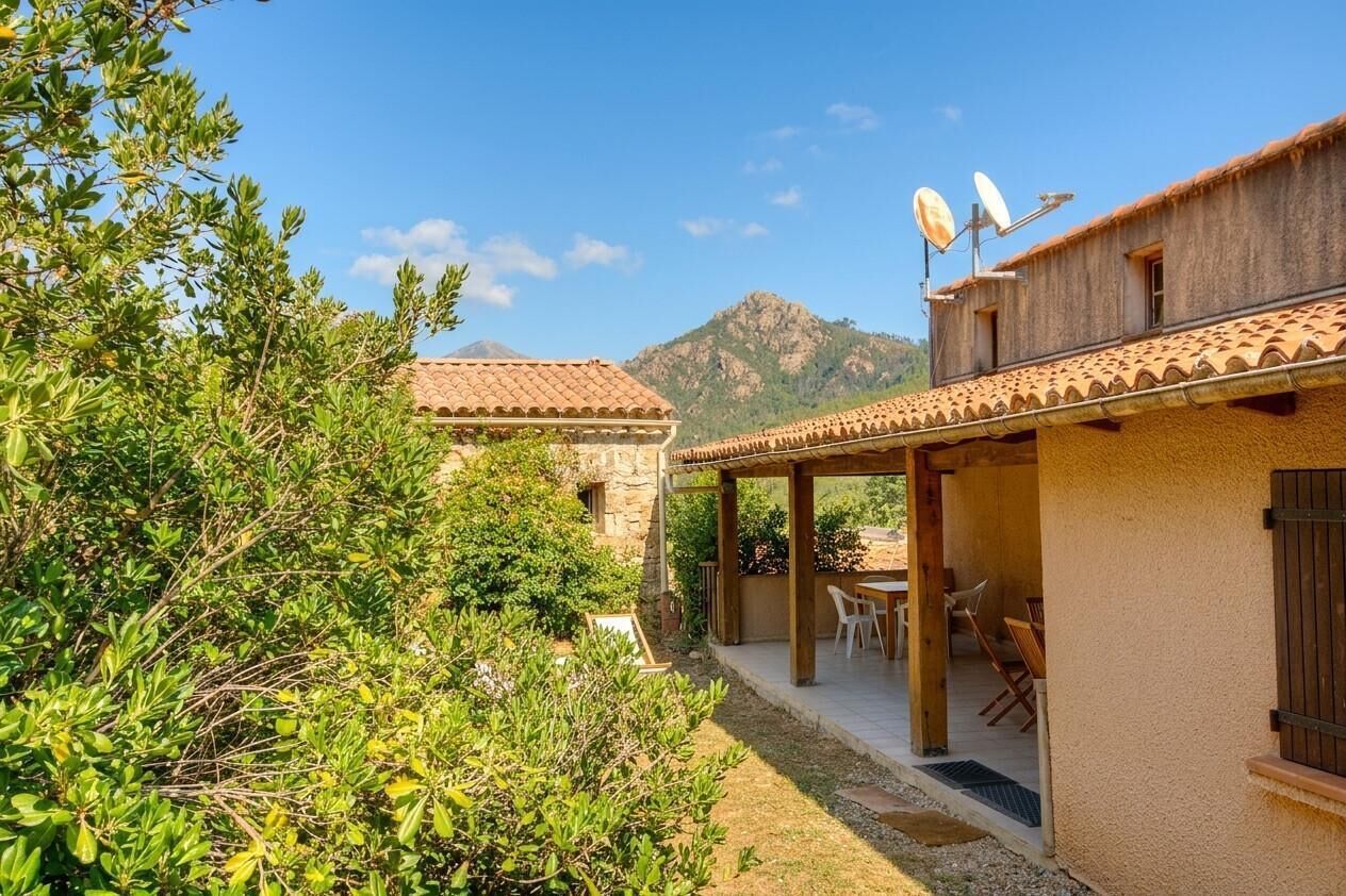 A building with a patio area, outdoor seating, and a mountain in the background.