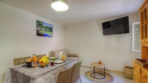 A dining area with a table set for two, a television mounted on the wall, and a wooden cabinet. - U Furconi - CHISA - Gîte (CHISA)