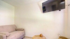 A living room with a sofa, a round coffee table, a flat-screen TV mounted on the wall, and a woven basket on the floor. - U Furconi - CHISA - Gîte (CHISA)