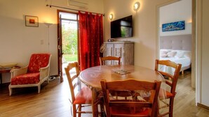 Una habitación con una mesa de comedor redonda de madera, sillas, un sofá, un televisor y una cama.