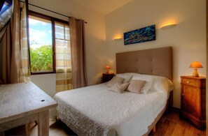 A bedroom with a bed, a table, a nightstand, a lamp, and a painting on the wall. - Papyrus - SANTA REPARATA DI BALAGNA (SANTA REPARATA DI BALAGNA)