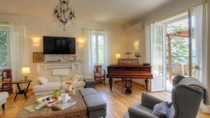 Uma sala de estar com televisão, piano, sofá e mesa de centro.