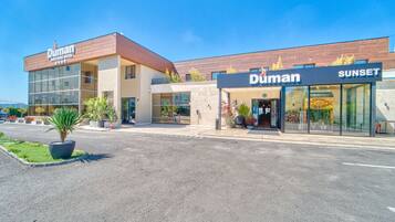Un hotel Duman de diseño moderno, con una entrada destacada y un área exterior visible con plantas en macetas.