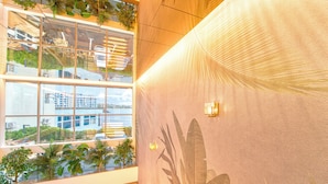 Un interior moderno con ventanas amplias, plantas de interior y una pared con textura.