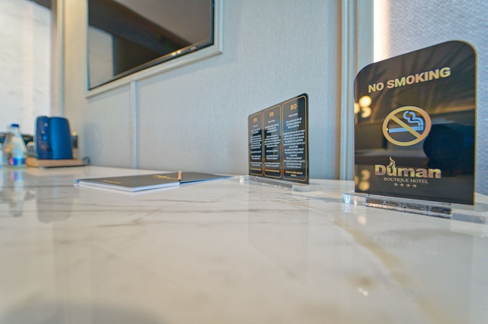 A hotel reception area with a 'No Smoking' sign, a digital screen, and a water dispenser.