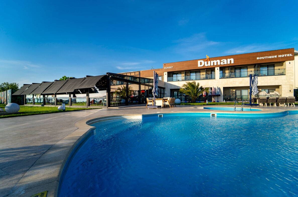A hotel with a pool, outdoor seating, and a covered area.