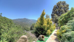 Ein Garten mit einem Pfad, einem großen Felsen und Blick auf die Berge.