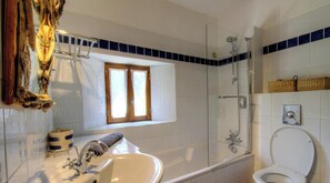 Une salle de bain avec une baignoire, des toilettes, une fenĂȘtre et une douche.