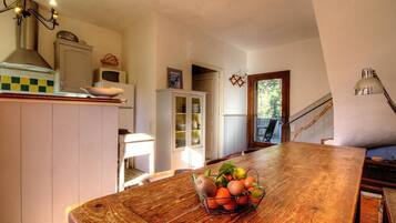Une cuisine avec une table en bois, un panier de fruits et un four à micro-ondes.