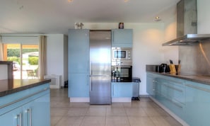 Una cocina moderna con una isla central, electrodomésticos de acero inoxidable y alacenas azul claro.