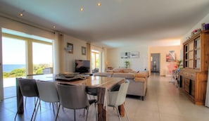 Un salón espacioso con una mesa de comedor, sillas, un sofá y una televisión.
