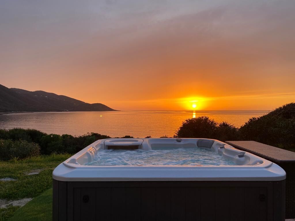 A hot tub with a sunset view over water.