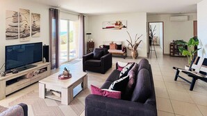 Een moderne woonkamer met een flatscreen televisie, banken, een salontafel en een eethoek.