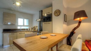 A modern kitchen with a dining table, chairs, a clock, and a unique lamp. - Casa Paterna - VENACO (VENACO)