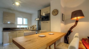 A modern kitchen with a dining table, chairs, a clock, and a unique lamp. - Casa Paterna - VENACO (VENACO)