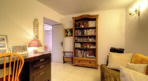A cozy living room with a wooden bookshelf, a desk with a lamp, a chair, and a sofa. - Casa Paterna - VENACO (VENACO)