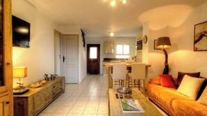 A living room with a sofa, a coffee table, a TV, and a kitchen in the background. - Casa Paterna - VENACO (VENACO)