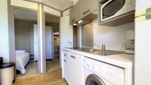 Uma cozinha compacta equipada com micro-ondas, pia e lava-louças.