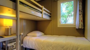 Quarto com beliche, janela, luminária de cabeceira e uma mesinha.