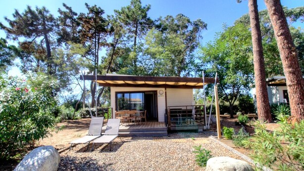 Uma área externa moderna com assentos, uma pérgola, uma mesa de pátio e cadeiras.