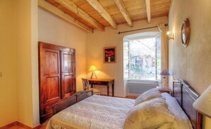 Ein Schlafzimmer mit zwei Betten, einem Holzschrank, einem Schreibtisch mit Lampe und einem Fenster mit Blick.