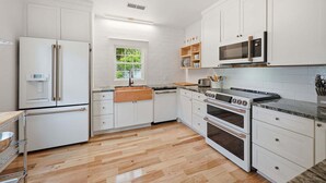 Eine moderne Küche mit weißen Schränken, einem eingebauten Ofen, einer Mikrowelle und einer Holz Arbeitsplatte.