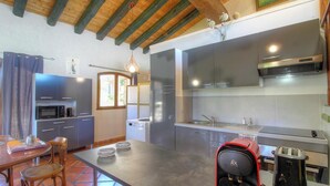 Una cocina compacta con electrodomésticos modernos, un comedor con mesa y sillas, y techo de madera.