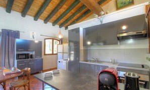 Een compacte keuken met moderne apparaten, een zithoek met een tafel en stoelen, en een houten plafond.