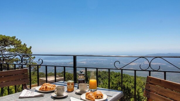 Una mesa con comida y bebidas, vistas del paisaje y una barandilla de balcón.